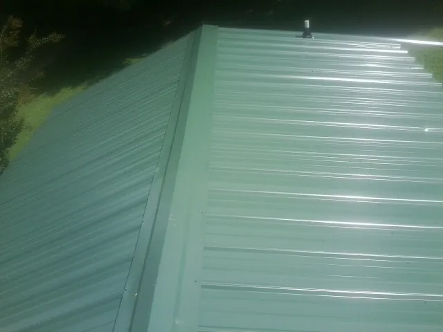 New green metal panels meeting at the ridge of a roof in Wellsville