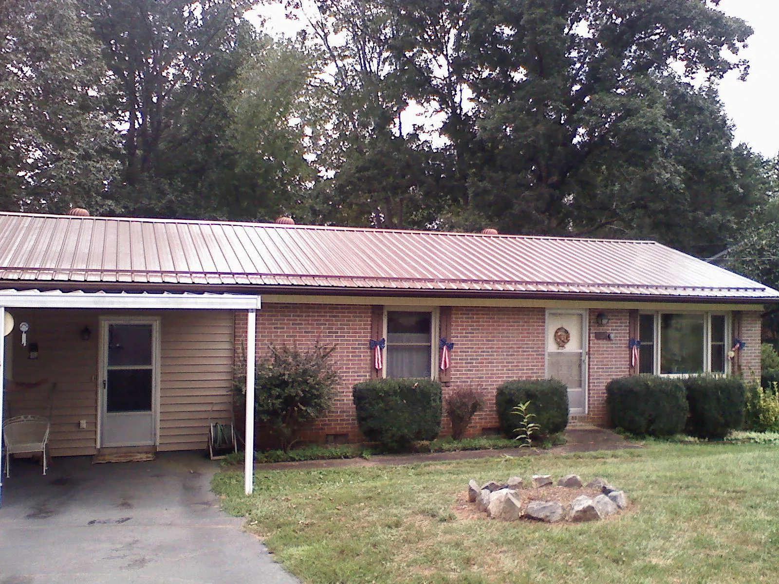 Bronze metal roof and carport on a brick ranch home — Roof Repair work by our crew in Wellsville